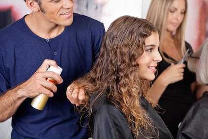 Hairdresser Fixing Woman's Hair With Spray