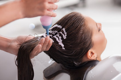 Attractive young girl is getting a hairwash in salon